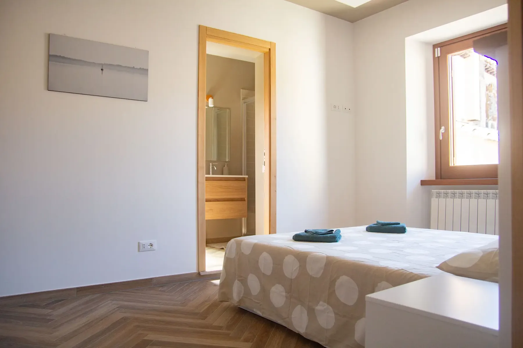 The double bedroom at Finestra sul Borgo, with its adjacent bathroom and window over the village